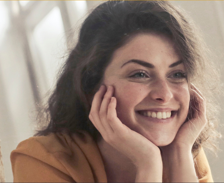 Young woman with Dental Bridges Hamilton smiling into mirror