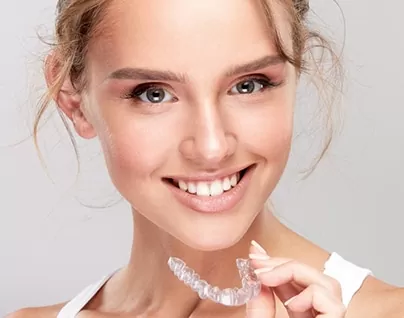 Stylish woman with bright smile holding Invisalign clear aligner