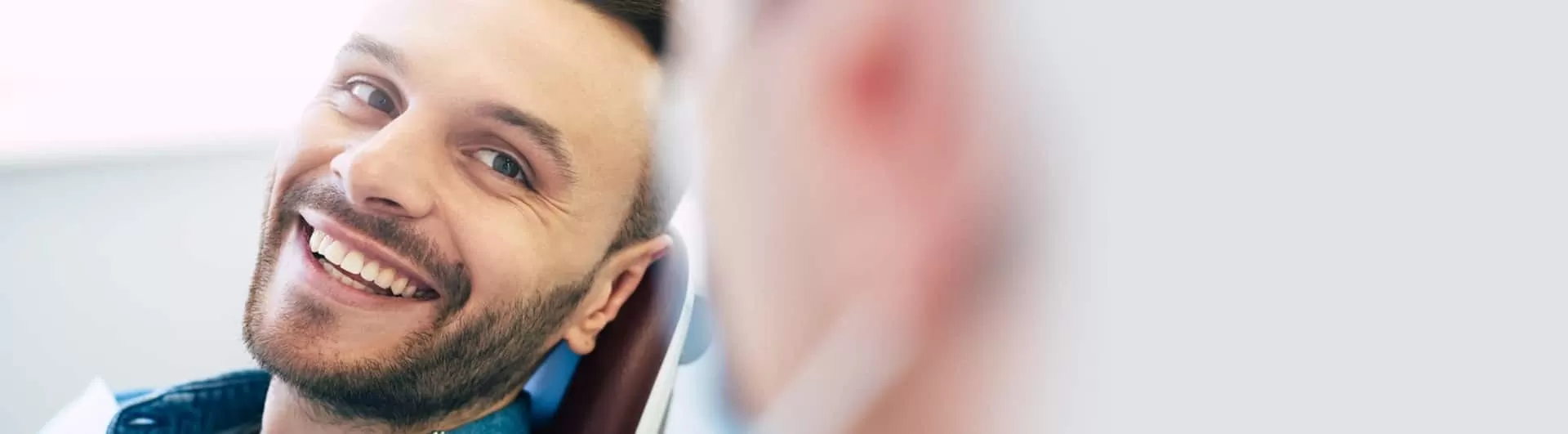 Young bearded man smiling in Hamilton dental chair