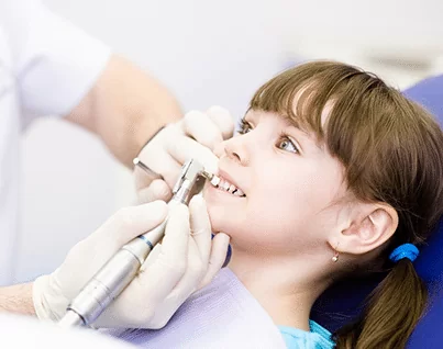 Dental hygienist polishing brave young girl's teeth