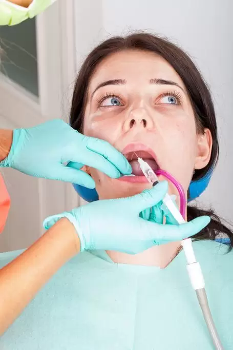 Emergency dentist helping panicked patient through painless procedure